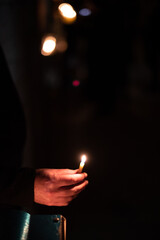 Closeup of a man's hand holding a candle and reciting the blessings prior to lighting the Hanukkah menorah during the eight-day Festival of Lights in Israel.