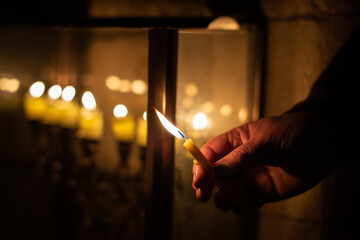 Closeup of a man's hand holding a candle and reciting the blessings prior to lighting the Hanukkah...