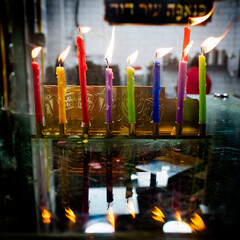 Multi-colored, wax Hanukkah candles burn in a menorah during celebration of the Jewish festival of...