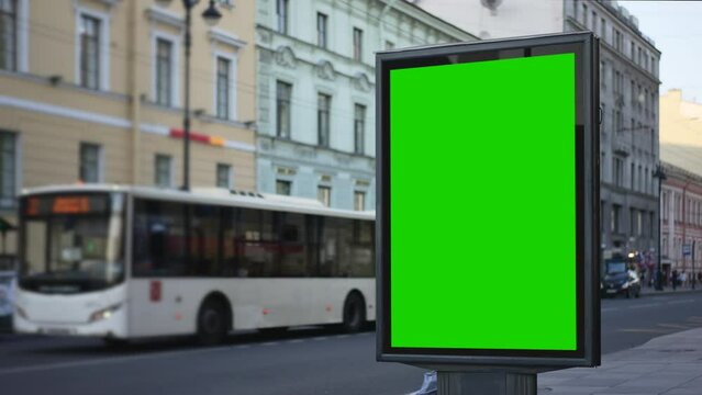 4k View of mockup screen, people and vehicles on city street spbd. Green billboard poster is standing, people walking along street and cars driving along road in town on summer day. Empty vertical