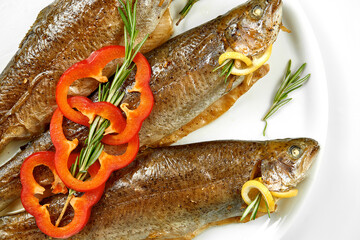 Fresh marinated in spices trout fish in a white plate. White background, selective focus
