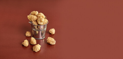 Textured pieces of soy flour in a small bucket on a brown background.