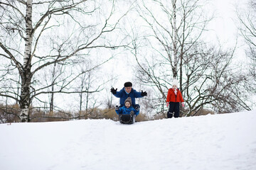 Children in the park in winter. Kids play with snow on the playground. They sculpt snowmen and slide down the hills.