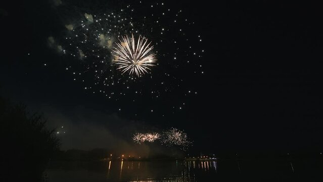 4k footage of beautiful Fireworks on Deep Black Background Sky on Fireworks festival from sail yacht over night city lights in summer river night trip. High quality 4k raw video