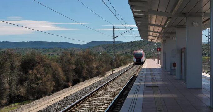 Tren de pasajeros moderno que ingresa a la estaci&oacute;n en el campo