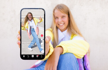 Teenage girl showing mobile phone with sample video content shared on social media - obrazy, fototapety, plakaty