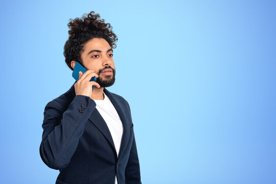 Arab businessman talking on the phone on blue background. Copy space