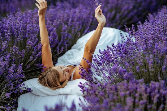 A middle-aged woman lies in a lavender field and enjoys aromatherapy. Aromatherapy concept, lavender oil, photo session in lavender