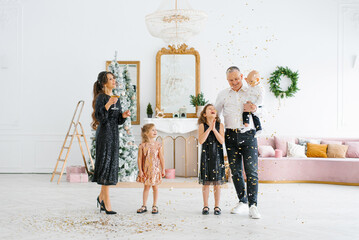 Family with young children playing with confetti at a New Year celebration, a homely atmosphere,...