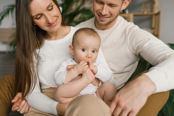 Mom, dad and six-month-old baby son in their arms spend time together in their cozy home