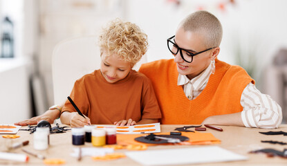 Young family mother  and child  preparing decorations for Halloween and engage in creativity