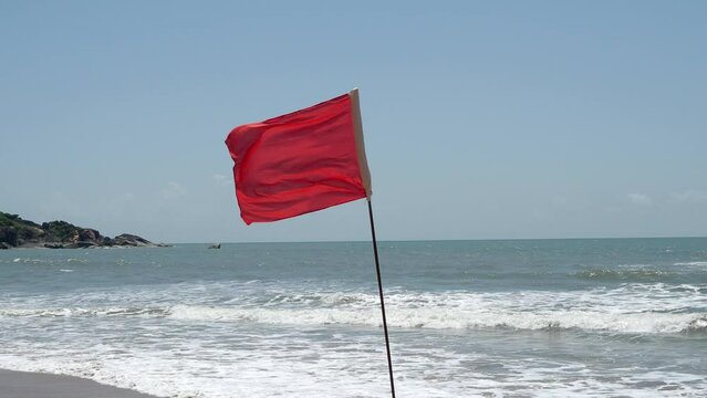 Red flag as warning sign on the beach before storm means no swimming,  during windy sunny day