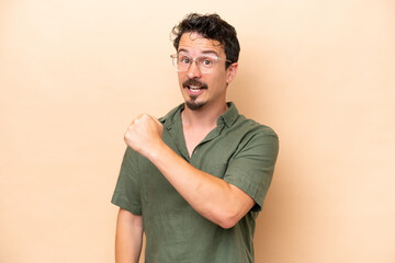 Young caucasian man isolated on beige background celebrating a victory