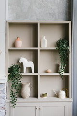 Fototapeta na wymiar Open cabinet with shelves decorated with vases and indoor plants in Scandinavian style