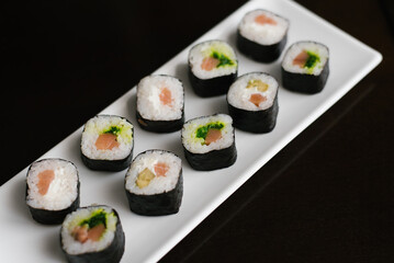 Rolls with salmon and chuka salad lie on a white rectangular plate