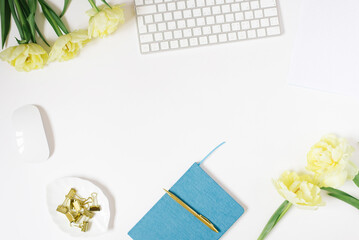Office desk with notepad, computer and tulip flowers. Top view with copy space