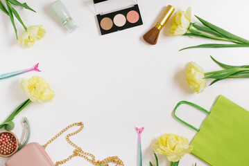 Yellow tulips, a gift box with a yellow ribbon and a bow, decorative cosmetics on a white background. Stylish flat lay fashion blogger with copy space