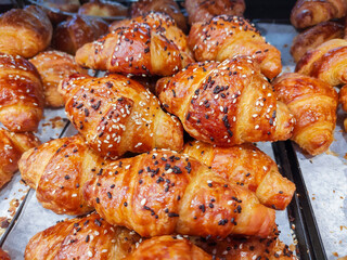 Small butter croissants with chocolate chips and white sesame for sale at the bakery store