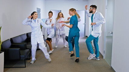 Charismatic doctors and nurses dancing excited in the hospital corridor they enjoying the time at...