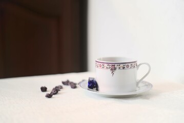 Tasse de thé violette et blanche avec des violettes cristallisées et un bonbon à la violette sur...