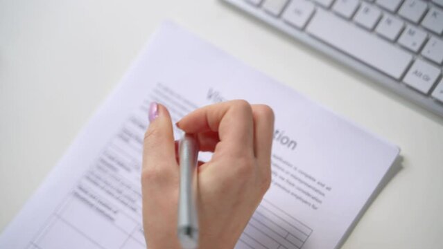 Person Hand Filling Visa Application Form