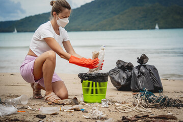 A female ecologist volunteer cleans the beach on the seashore from plastic and other waste