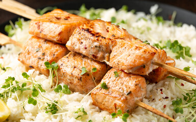 Salmon kebab on skewers served with jasmine rice and lemon wedge