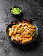 Tteokbokki, Topokki fried rice cake stick in black bowl. Korean street food