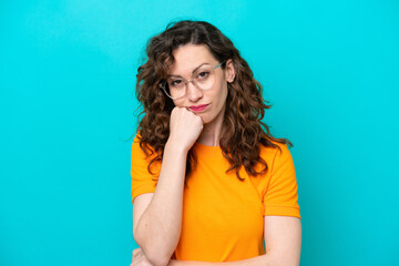 Young caucasian woman isolated on blue background With glasses and with sad expression