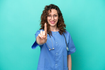 Young nurse caucasian woman isolated on blue background showing and lifting a finger