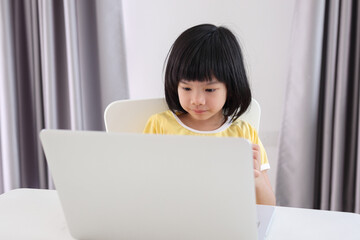 little asian girl student study online using laptop computer at home