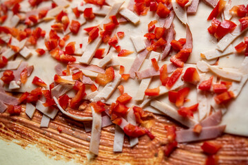 Detail of toppings on puff pastry. Ham, pepper, corn, and garlic sauce spread over the dough