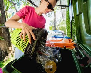 A young beautiful girl throws sorted garbage into special bins