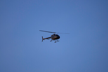 Fototapeta na wymiar Mały pasażerski śmigłowiec lecący na tle bezchmurnego, błękitnego nieba.