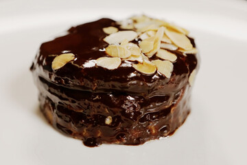 Round dessert opera with chocolate and almonds on a white plate. French cuisine. Top view.