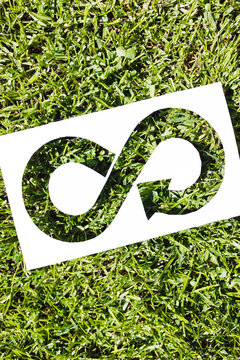 ecology and sustainability, circular economy symbol on paper cutout with perfect green grass filling it