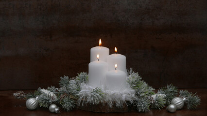 Vier weiße brennende Adventskerzen vor einem dunklen Hintergrund.