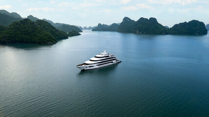 beautiful white luxury mega yacht in tropical Ha Long Bay Vietnam with large limestone mountains,...