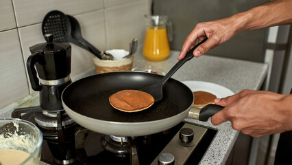 Cropped of man taking pancake after cooking on pan