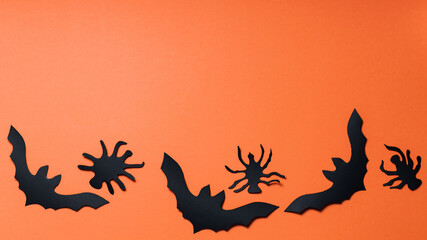 Halloween background with bats and spiders on orange background. Halloween paper decorations. Copy space