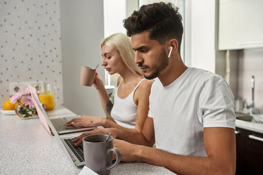 Couple working on laptops at table at home kitchen