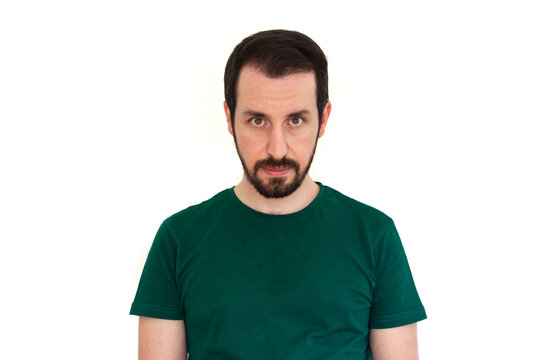 Portrait of an angry face of a young caucasian man isolated on a white background. Modern Turkish guy is wearing green t shirt.