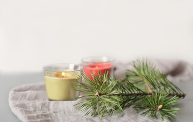 Obraz na płótnie Canvas winter holiday or weekend ambient still life. glowing soy wax candles in glass pots and pine tree needles on soft textile tablecloth. cozy home, calm and peaceful decor for fall season
