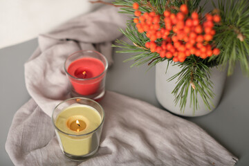 rowanberry and pine branch in a concrete vase and glowing candles on grey background. blog autumn content.
