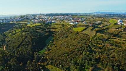 Top view of a European town with beautiful green landscape during sunset. Drone view of a beautiful small European city with a beautiful hilly landscape while sunset.  Portugal.