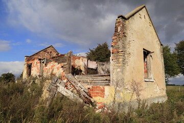 Stary opuszczony dom popada w ruinę. Stoi gdzieś na polach przy drodze.