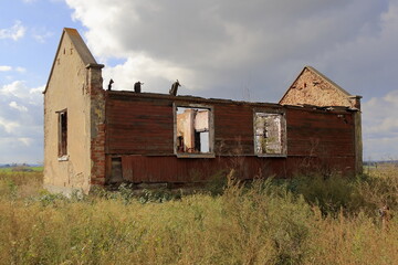The old abandoned house is falling into disrepair. It stands somewhere in the fields by the road.