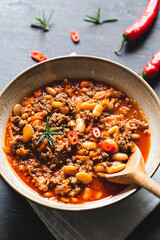 Chili Con Carne in bowl on dark background. Mexican cuisine. chili con carne - minced meat and vegetables stew in tomato sauce. Top view