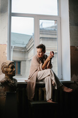 Portrait of a mature woman on a windowsill in low key.