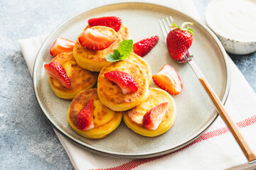 Cottage cheese pancakes, ricotta fritters or syrniki with mint and strawberries. Healthy and delicious morning breakfast.
